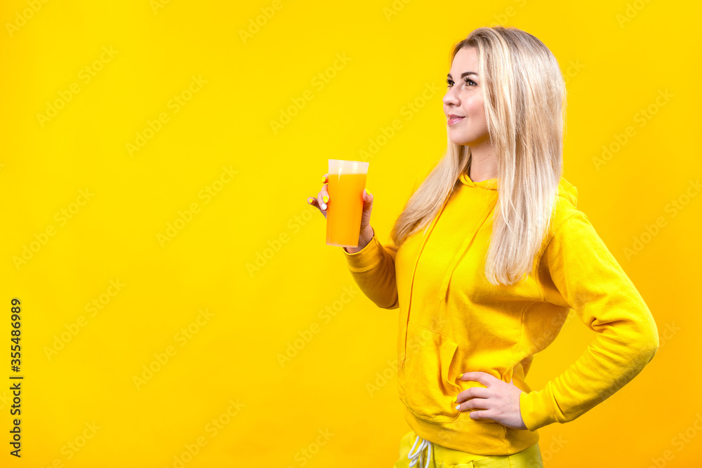 Attractive beautiful young blonde woman in yellow casual sporty clothes holding orange juice glass, Attractive beautiful young blonde woman in yellow casual sporty clothes holding orange juice glass,
