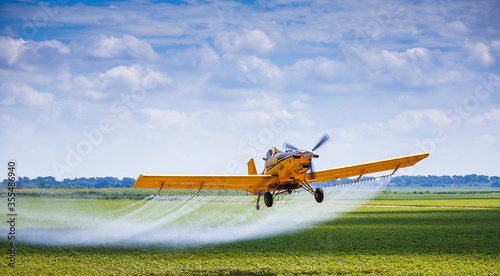 Yellow Crop Duster Airplane Aerially Applies Pesticide to Cotton Fields in Texas photo
