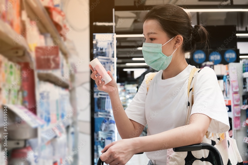 Asian girl in with t-shirt with yellow bag wear surgical mask to protect the Covid-19 in supermarket, New normal lifestyle.