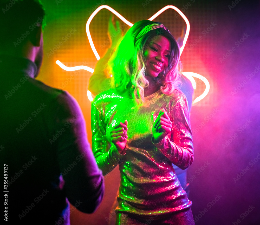 Pretty woman dancing in night club. Sexy African women in shiny dress have  fun dancing with friends in bright neon lights at night disco. Discotheque  concept. Stock Photo | Adobe Stock