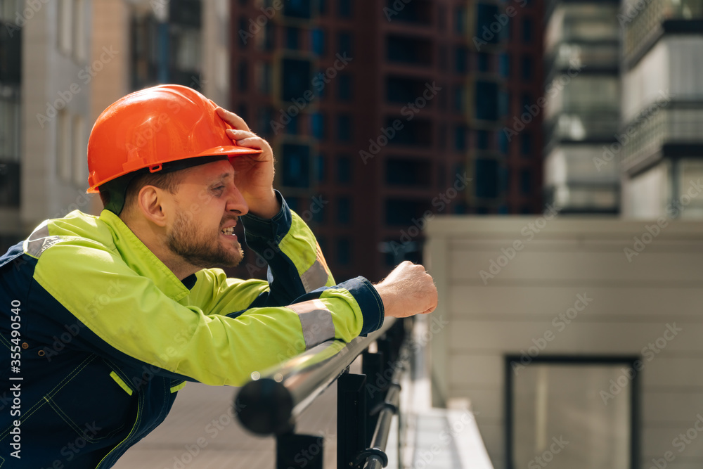 Spastel young man in a helmet close-up, upset in shock, holding his head. The concept of saving people's lives Spastel young man in a helmet close-up, upset in shock, holding his head. The concept of saving people's lives