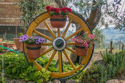 Garden with wooden wheel with vase of flowers
