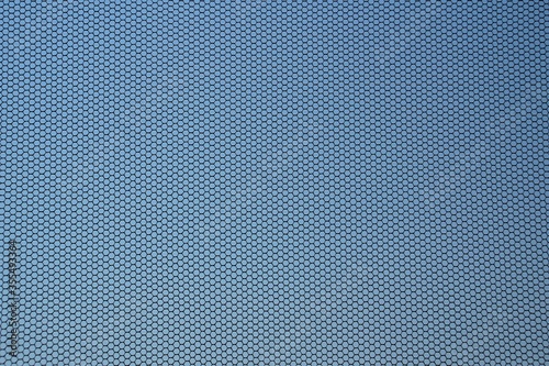 Close up of black fly screen with blue cloudless sky in background. Mosquito net fixed on a window. Insect screen. Contre-jour shot.