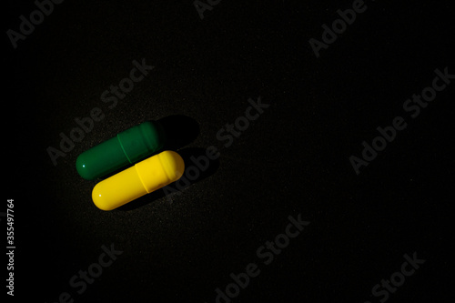 Dois comprimidos coloridos em verde e amarelo em fundo preto.