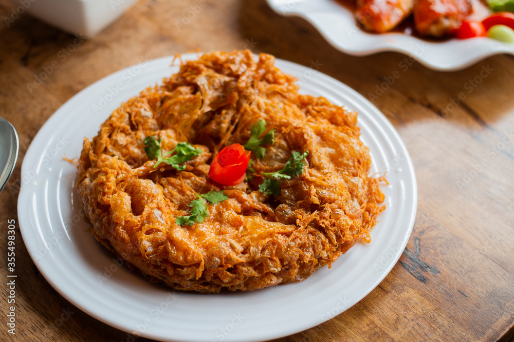 Top view of delicious Thai style omelet serves on white plate on wooden table. Top view of delicious Thai style omelet serves on white plate on wooden table.