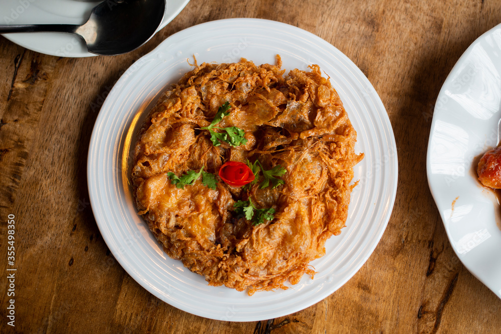 Top view of delicious Thai style omelet serves on white plate on wooden table. Top view of delicious Thai style omelet serves on white plate on wooden table.