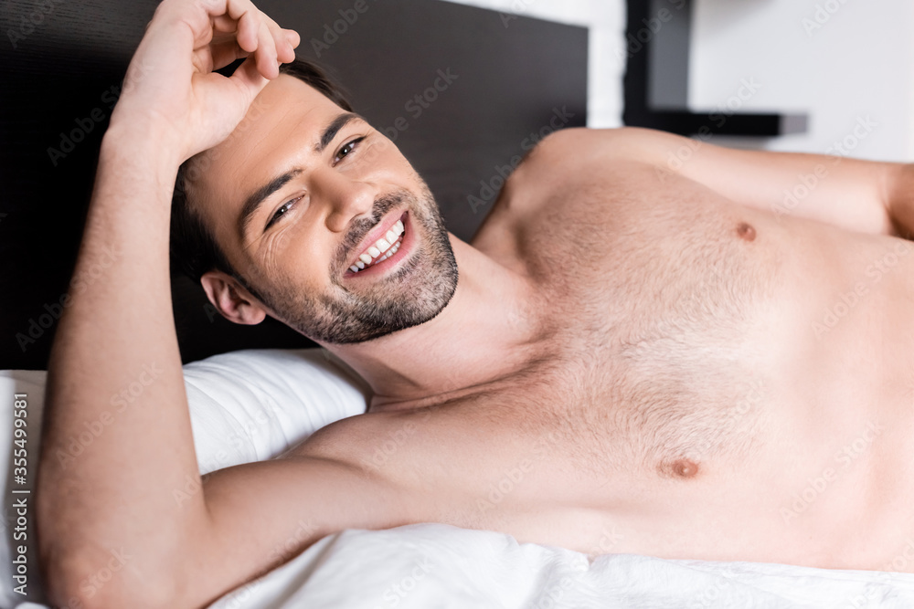 Obraz premium happy sexy shirtless man lying on bed at home