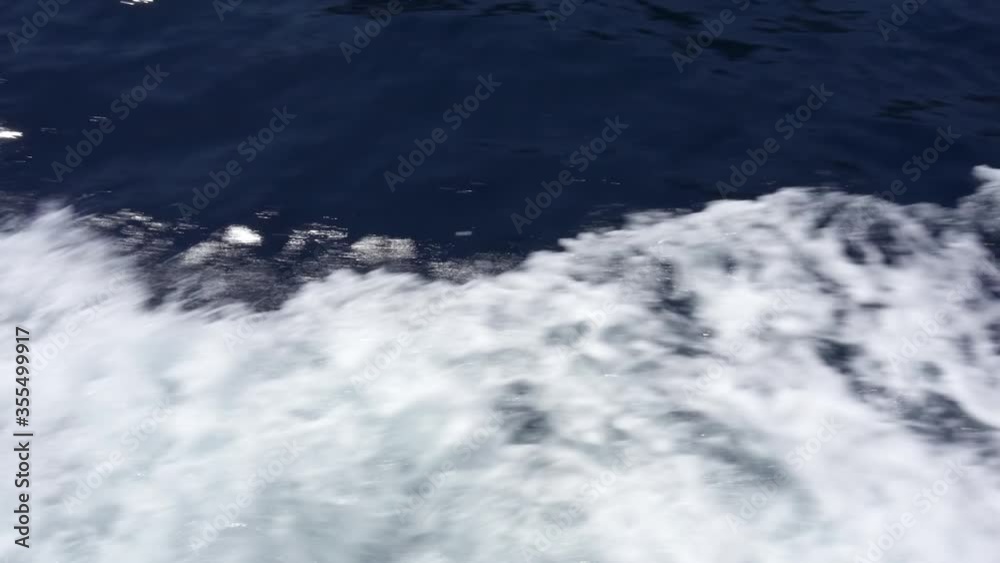 Close up of waves trail behind motor boat at summer sunny day. Beautiful deep blue Mediterranean sea at French Riviera. Handheld camera, natural shaking from boat trip Close up of waves trail behind motor boat at summer sunny day. Beautiful deep blue Mediterranean sea at French Riviera. Handheld camera, natural shaking from boat trip