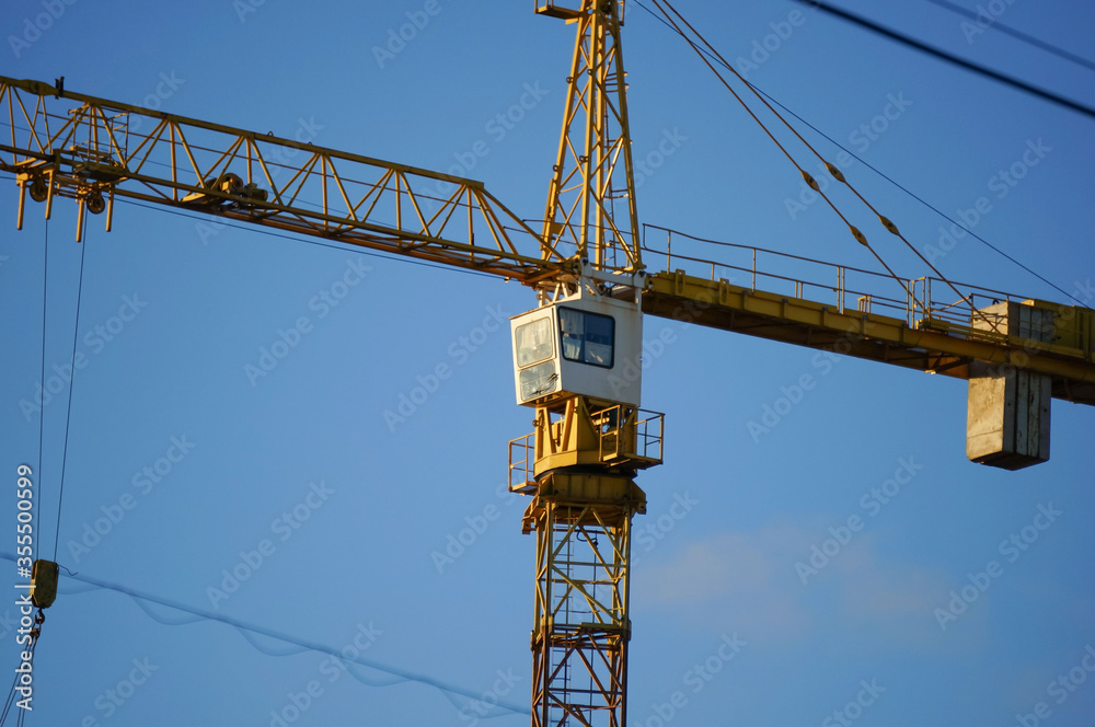 Hoisting construction crane on a background of blue sky. Construction works