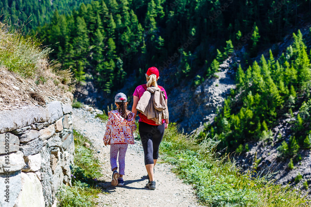 Mother with daughter hikers trekking in mountains.