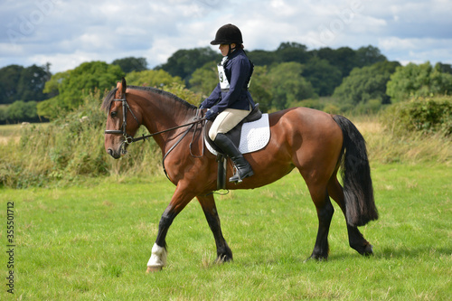 Smartly turned out young woman and her horse competing in a dressage competition outsides in the English countryside.