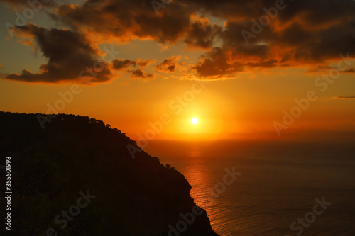 Sunset over sea with clouds and mountain rock in dusk – Mallorca coast, Spain