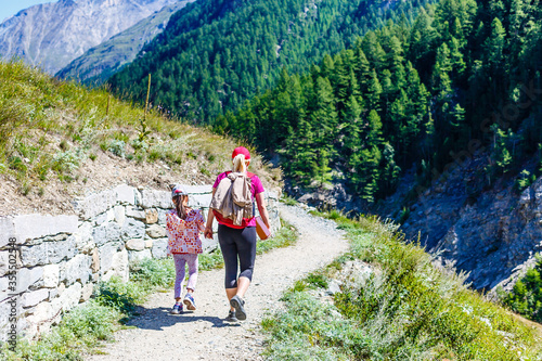 Mother with daughter hikers trekking in mountains.