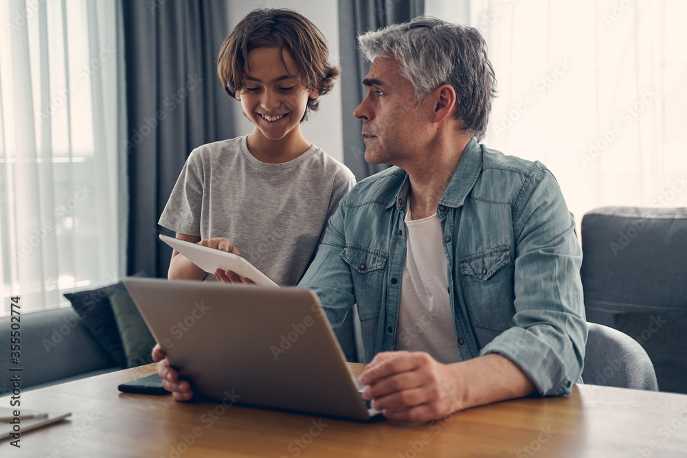 Grey haired male showing his son something on gadget Grey haired male showing his son something on gadget