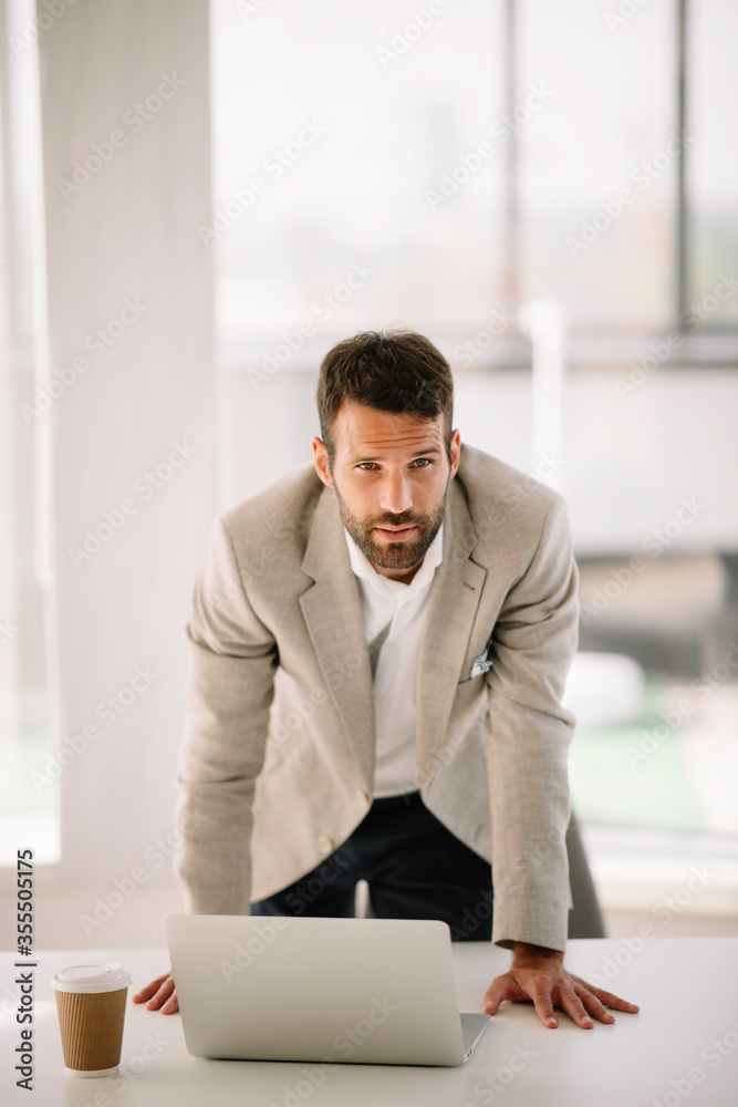 Portrait of handsome businessman. Man working on lap top and drinking coffee Portrait of handsome businessman. Man working on lap top and drinking coffee