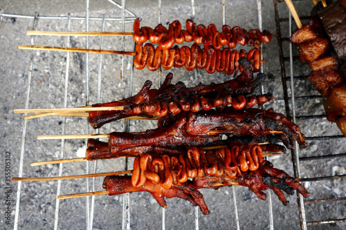 Grilled chicken and pork innards sold at a street food cart along a sidewalk photo