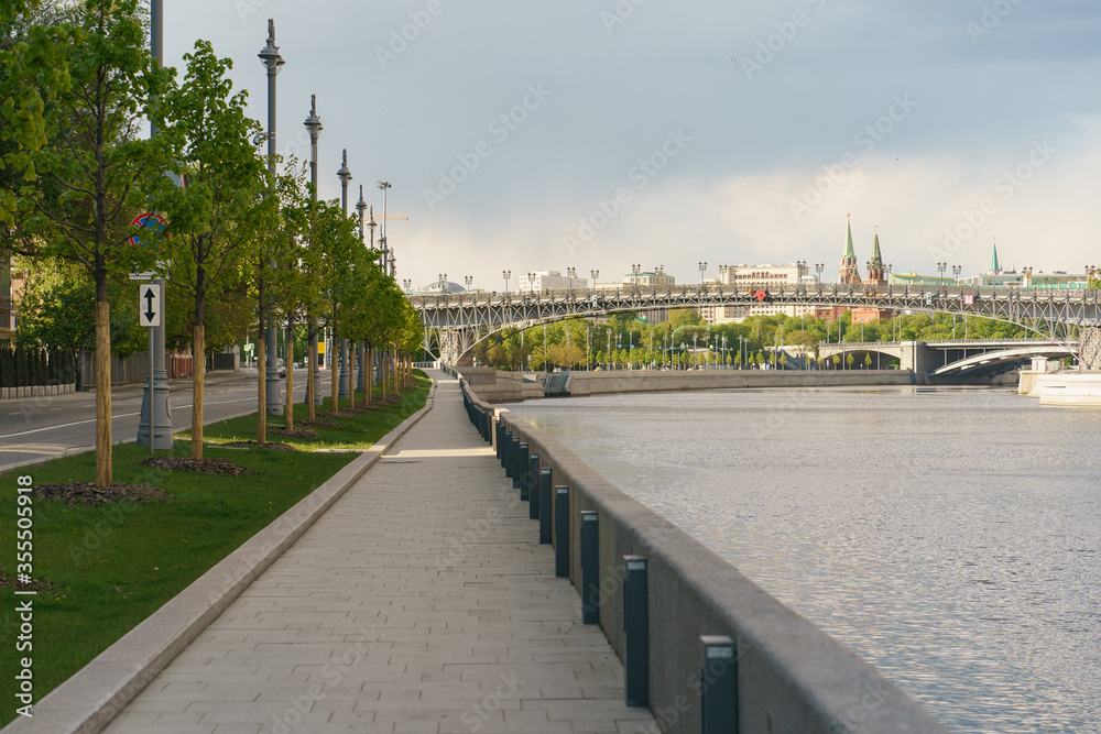 Wide and calm Moscow cityscape. Prechistenskaya embankment. Moskva river. Patriarshy Bridge. Kremlin Towers in distance.