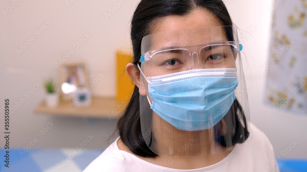 Portrait of an Asia young female who is wearing a face shield with mask rounded around her face from a frontal perspective to protect her glasses and eyes prepare to new normal. Coronavirus pandemic.