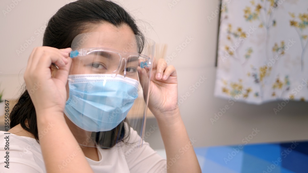 Portrait of an Asia young female who is wearing a face shield with mask rounded around her face from a frontal perspective to protect her glasses and eyes prepare to new normal. Coronavirus pandemic.