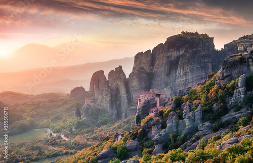 Amazing sunset with colorful sky over the fairytale mountain valley in Greece. Incredible sandstone rock formations under sunlit. Famouse Holy Monastery of St. Nicholas Anapausas. Meteora, Kalambaka,