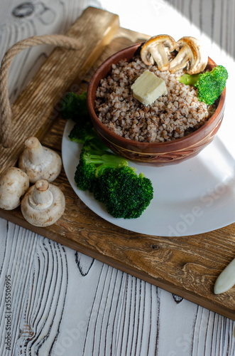 buckwheat porridge in a clay plate with butter and broccoli