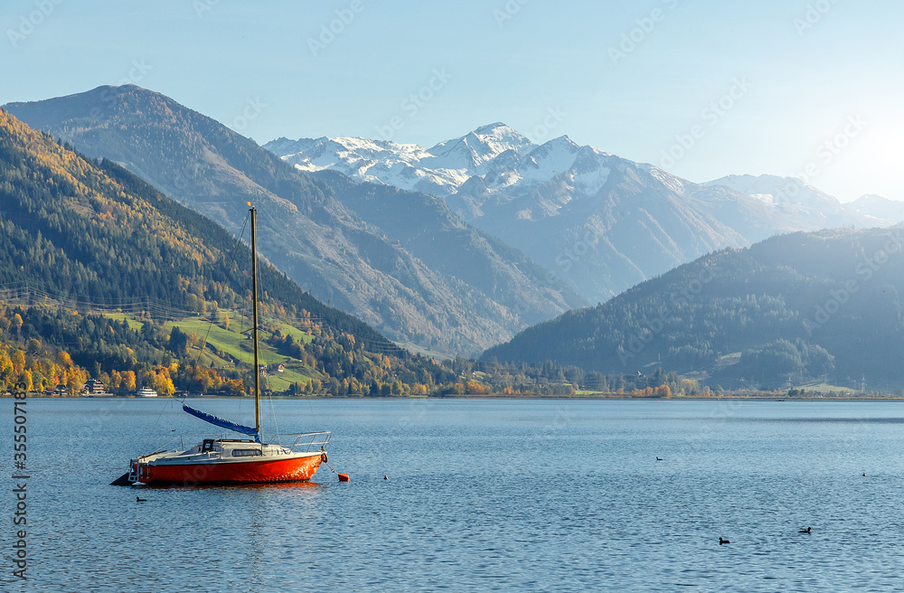 Fantastic views of the turquoise lake Zeller, under sunlight. Panoramic view on mountain lake with yaht, in front of mountain range. Awesome nature background. Landscape in Alps in sunny day.