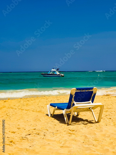 Blue sun lounge on the beach in Punta Cana with a boat in the background. © Valentina Sandu