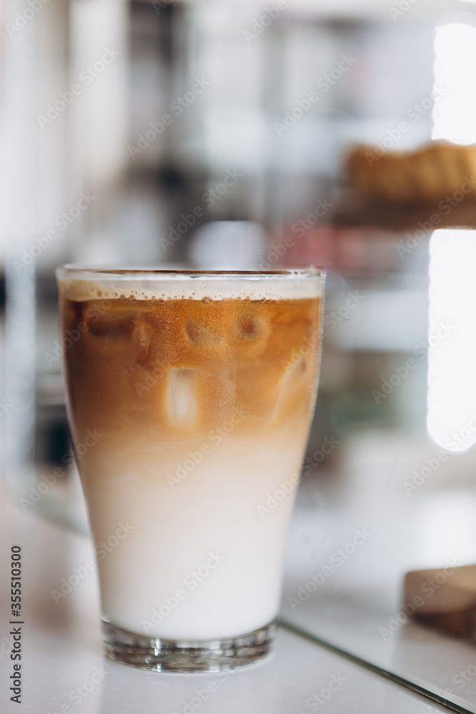Glass with coffee, milk and ice on cafe background Glass with coffee, milk and ice on cafe background