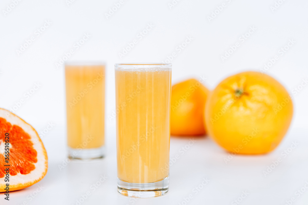 Glass with grapefruit juice and whole and sliced grapefruit on the background Glass with grapefruit juice and whole and sliced grapefruit on the background