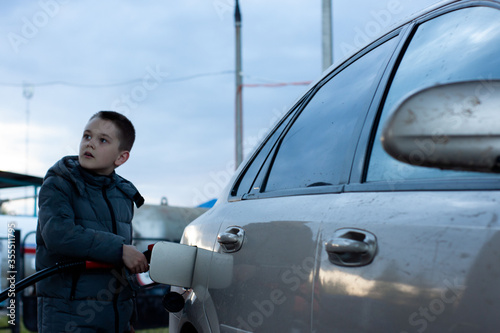 a boy refuels a car at a gas station. gas station. petrol