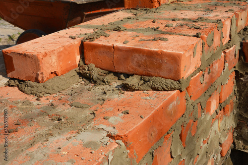 A close-up on bricklaying one and a half brick foundation wall using mortar during house construction.