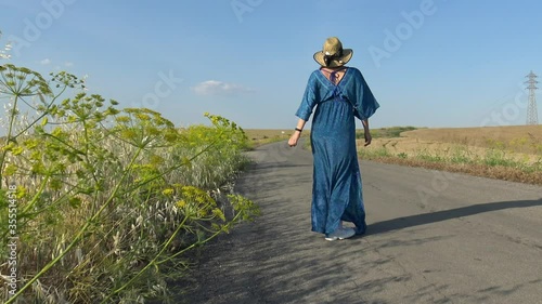 Mujer caminando por la carretera con un vestido azul, en movimiento  photo