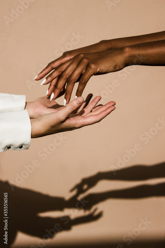 black and white hands reaching towards eachother with shadows