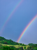 Double rainbow over the hill on the dark sky