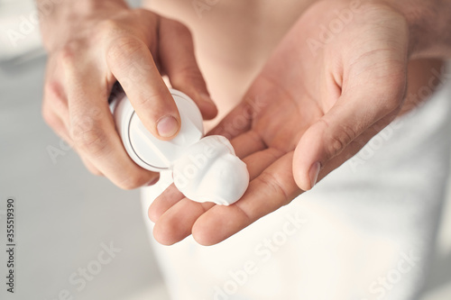 Hands of a man pouring some shaving foam out of dispenser