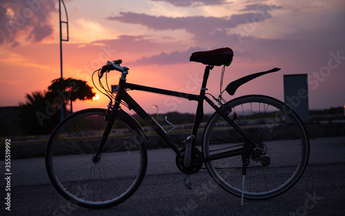 Silhouette of a bicycle with clouds and sunset in the background
