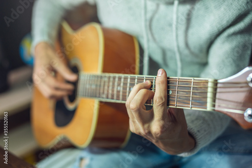 Young musician is learning to play the acoustic guitar. A man is playing a guitar close up