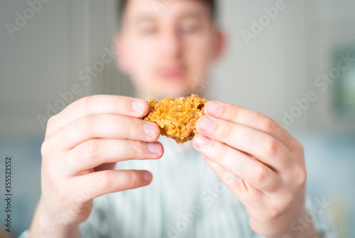 A hungry man looks at a chicken. Guy twists a fried chicken wing in his hands