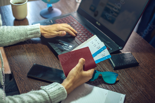 Man is buying air tickets over the Internet using a laptop for a trip. Online purchase and booking of travel tours photo