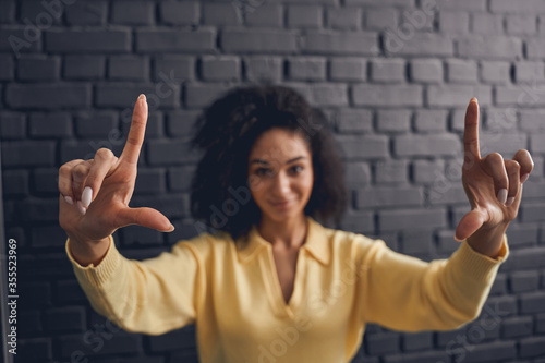 Focused curly-headed lady showing a hand gesture