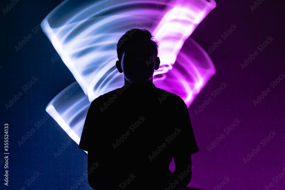 silhouette of a man in an abstract, double exposed neon blue and purple light