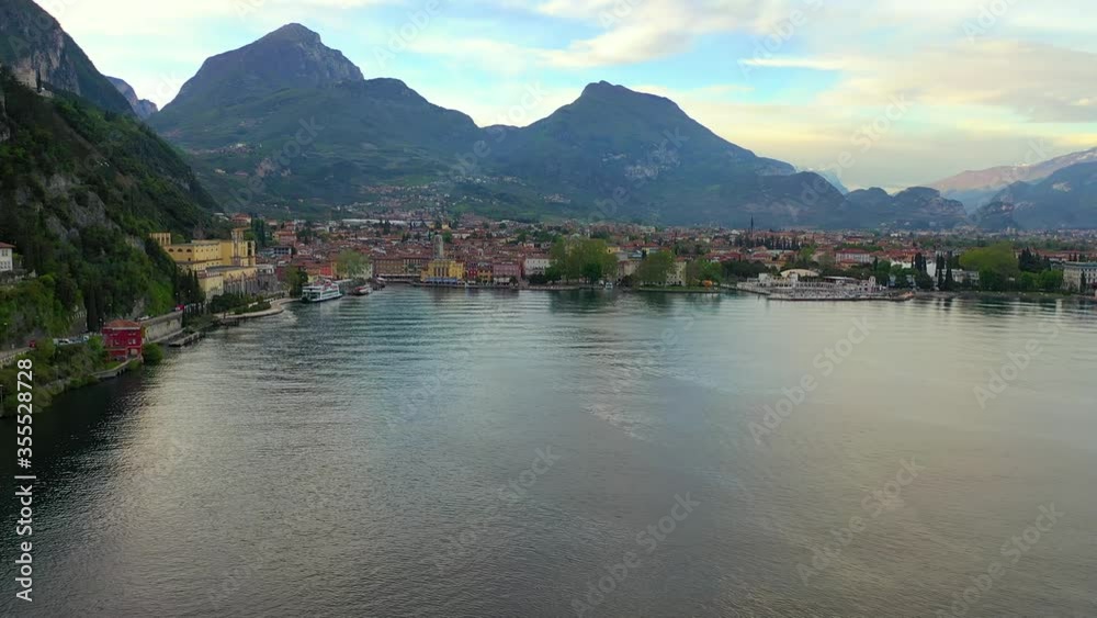 Aerial video with drone, view of the beautiful Riva del Garda town and Lake Garda lake surrounded by mountains in the autumn time , Trentino Alto Adige region, Lago di garda, italy
