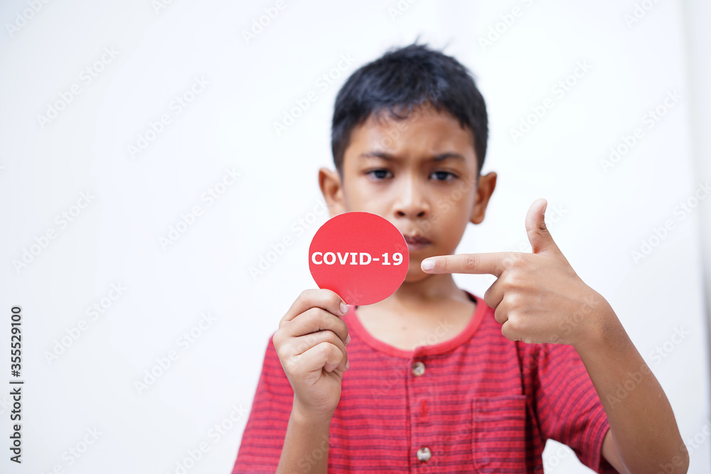 Asian boy holding Covid-19 sticker. Conceptual image for Stop the coronavirus spreading Asian boy holding Covid-19 sticker. Conceptual image for Stop the coronavirus spreading
