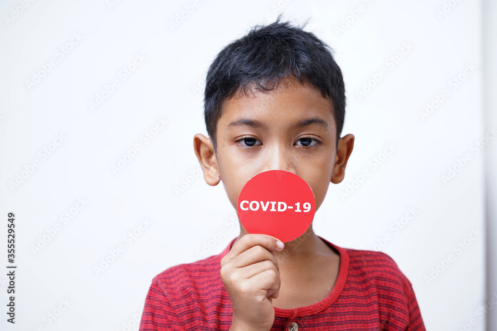 Asian boy holding Covid-19 sticker. Conceptual image for Stop the coronavirus spreading Asian boy holding Covid-19 sticker. Conceptual image for Stop the coronavirus spreading