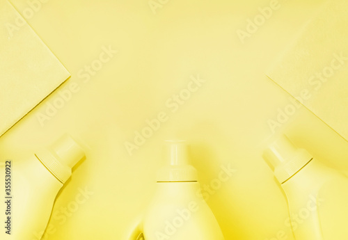 Plastic bottles with chemicals for cleaning, rags for cleaning. Yellow tinting, yellow background. Cleaning concept