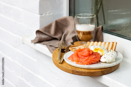 Poached egg with smoked salmon  toasted bread and coffee on white windowsill.