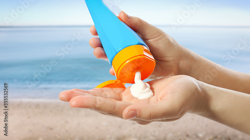 фотографія Young woman applying sun protection cream near sea, closeup