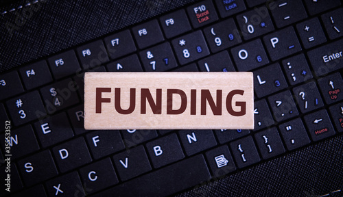 Funding - text on a wooden object on a black keyboard