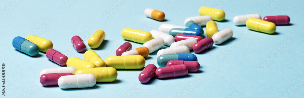 Multi-colored pills on a blue background close-up. Medical concept