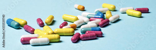 Multi-colored pills on a blue background close-up. Medical concept